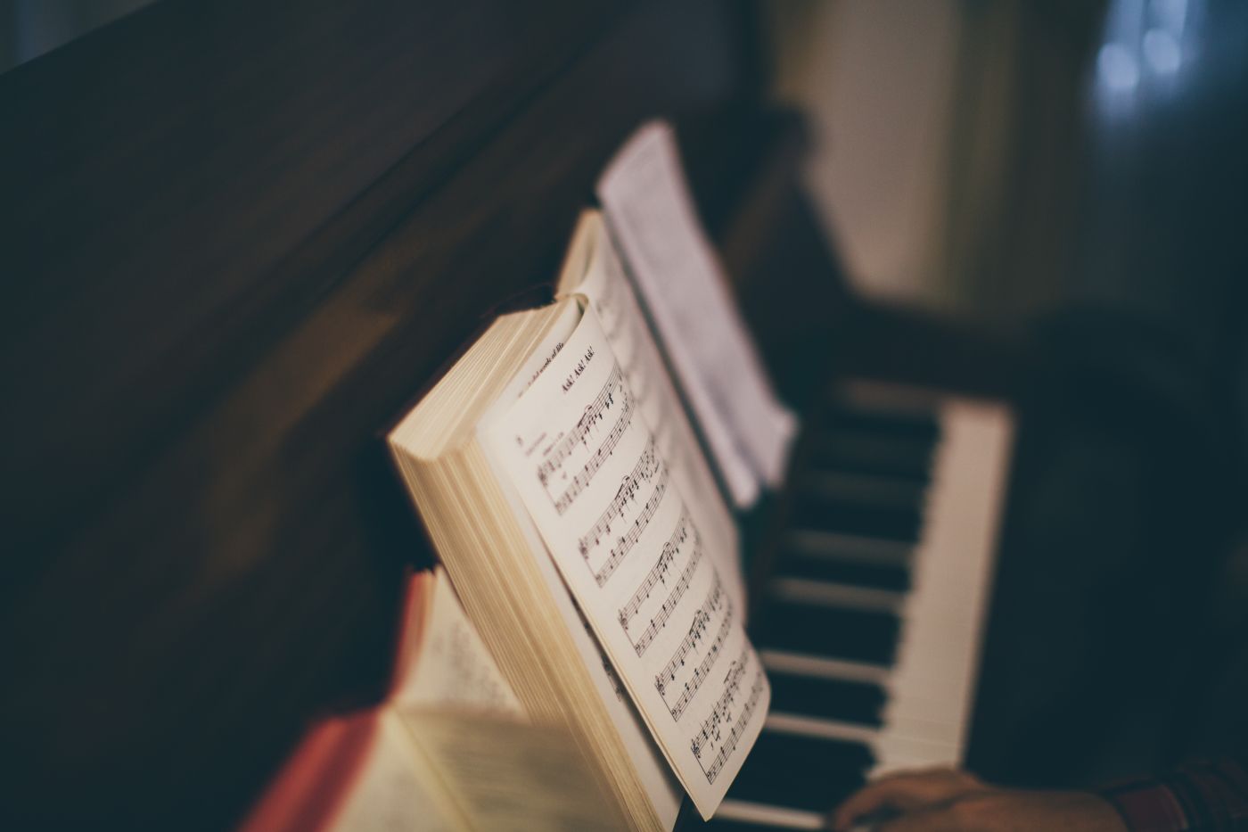 Une partition ouverte sur le pupitre d'un piano, les mains sur le clavier